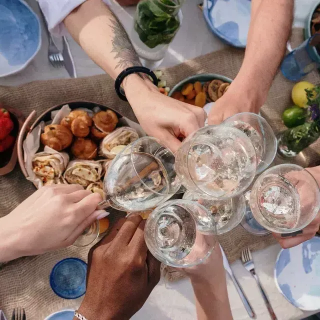 Foto aérea de um grupo de pessoas tilintando copos em uma mesa de brunch.