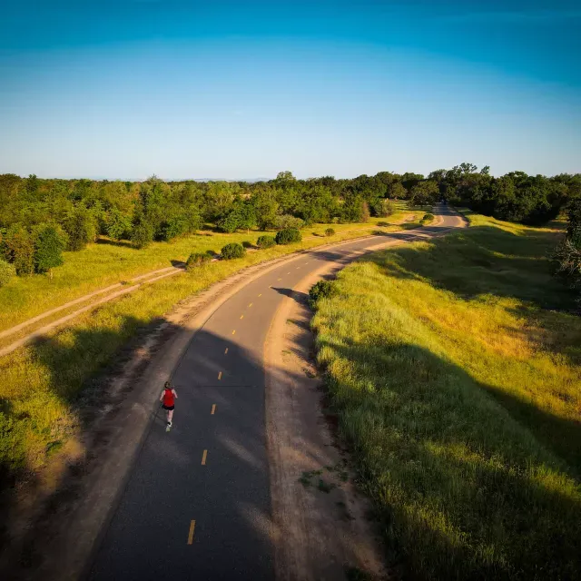 Fotografía cenital de una mujer corriendo por una carretera por el campo